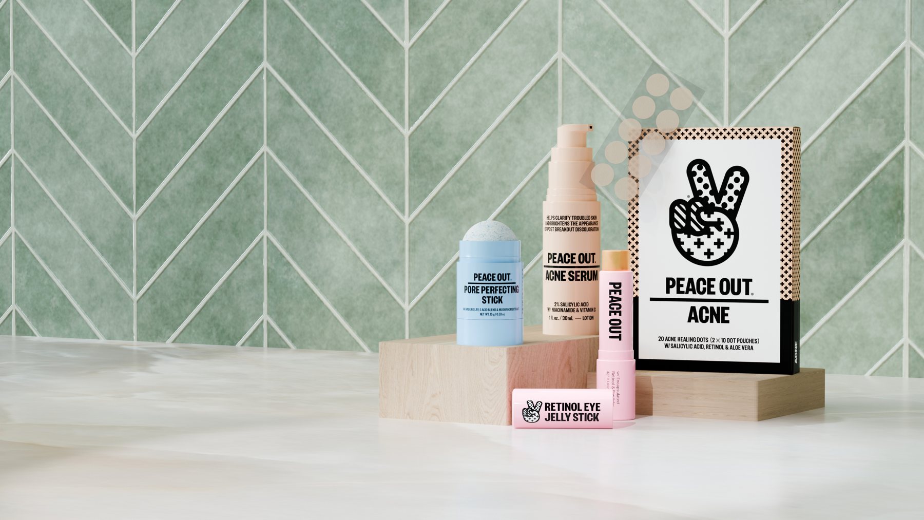 Peace Out acne serum, pore stick, eye jelly stick and acne dots box on wooden blocks against green chevron tile
